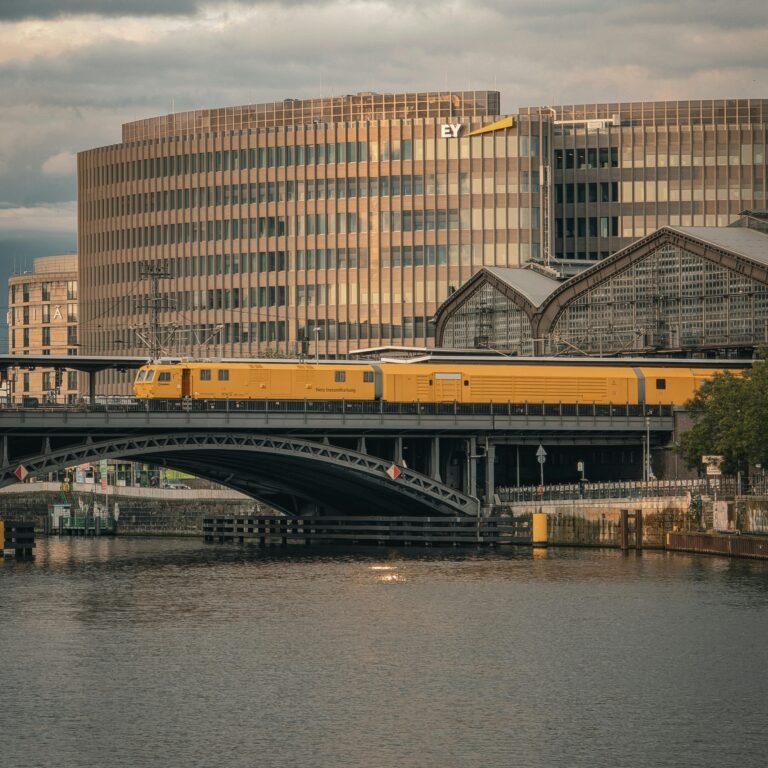 A beautiful view of a yellow train crossing a bridge in Berlin during sunset, showcasing modern architecture.