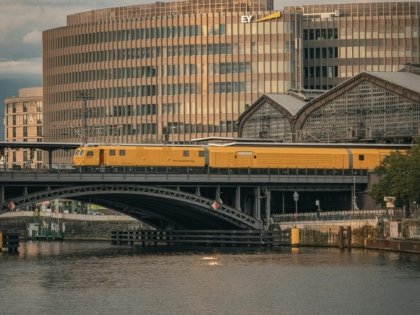 A beautiful view of a yellow train crossing a bridge in Berlin during sunset, showcasing modern architecture.
