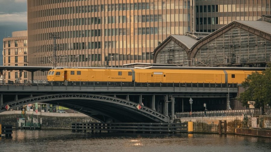A beautiful view of a yellow train crossing a bridge in Berlin during sunset, showcasing modern architecture.